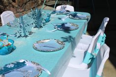 the table is set with blue and white plates, napkins, and silverware