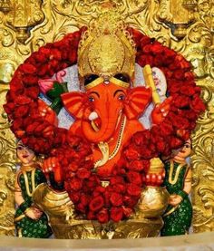 there is a statue of an elephant surrounded by red roses and other decorations on the wall