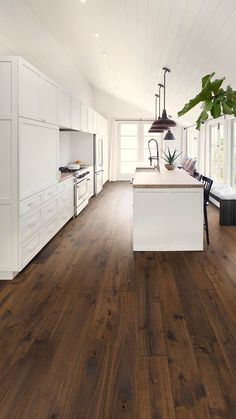 a large kitchen with white cabinets and wood flooring in the center is an island