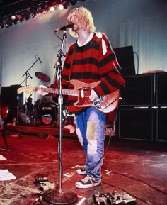 a man standing on top of a stage holding a guitar