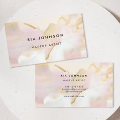 two business cards sitting on top of a white plate with gold foil paint and flowers