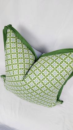 a green and white pillow on top of a bed with pillows in the shape of an ornament