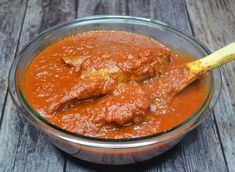 a glass bowl filled with red sauce on top of a wooden table