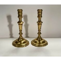 two brass candlesticks on a white table