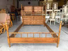 a wooden bed frame sitting in a room with lots of chairs and tables behind it