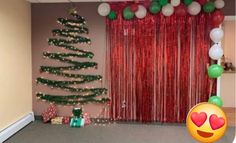 a decorated christmas tree in an office cubicle with balloons on the wall and a red curtain behind it