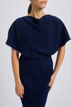 a woman is wearing a blue dress with an asymmetrically shaped neckline