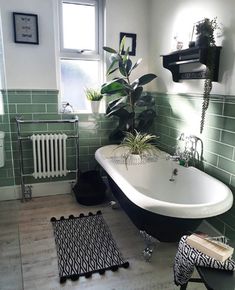 a bath tub sitting next to a window with green tiles on the walls and floor