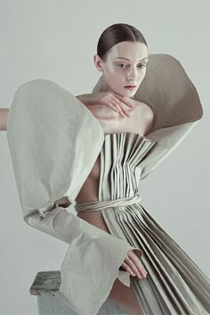 a woman in a white dress with her hands on her chest, posing for the camera