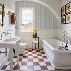 a bathroom with a checkered floor and white tub next to a sink, toilet and window