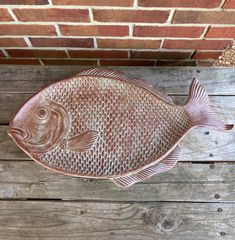 a fish shaped dish sitting on top of a wooden table next to a brick wall