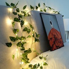 a bed with plants growing on the headboard and lights strung from it's sides