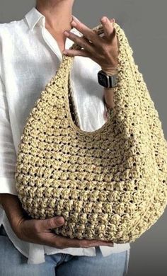 a woman holding a crocheted purse in her hands