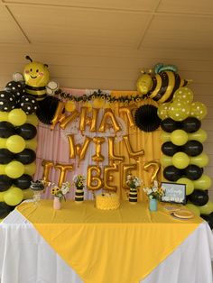 a table topped with balloons and decorations for a bee themed birthday party