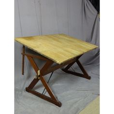 a wooden table sitting on top of a white sheet covered floor next to a wall