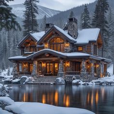 a large log home sitting on top of a snow covered hillside next to a lake