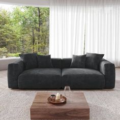 a living room with a couch, coffee table and large window in the back ground