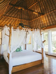 a white bed sitting inside of a bedroom on top of a hard wood floor