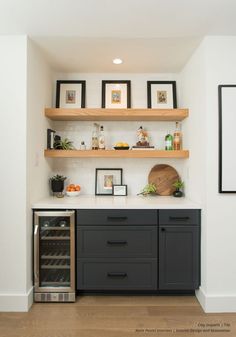 a kitchen with black cabinets and shelves filled with wine bottles on top of wooden shelves