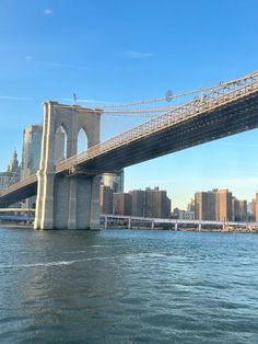 a bridge spanning the width of a large body of water with tall buildings in the background