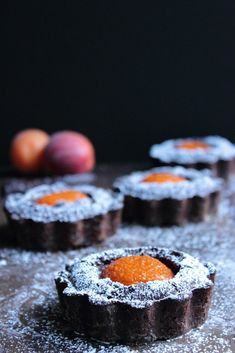 small pastries covered in powdered sugar sit on a table next to peaches