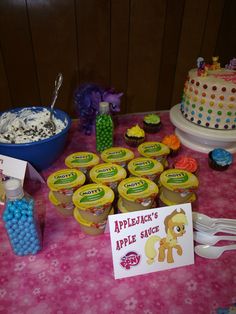 a table topped with lots of cupcakes covered in frosting next to a sign