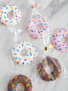 four donuts with sprinkles in plastic bags on a marble counter top