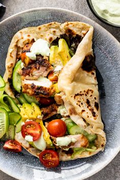 two pita sandwiches on a plate with cucumbers and tomatoes