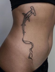 a woman's stomach with a dolphin tattoo on her lower back and side view