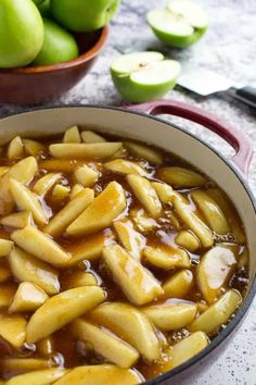 a pot filled with apples and sauce on top of a table