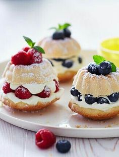 small pastries with berries and blueberries are on a white plate