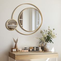 a mirror on the wall above a table with some books and other items next to it