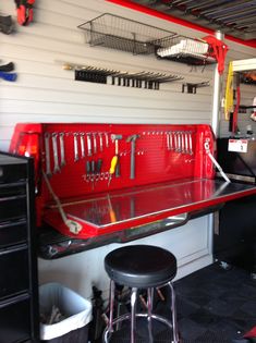 there is a red toolbox in the garage with tools hanging from it's ceiling