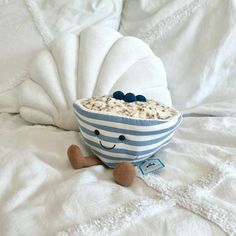 a blue and white bowl with cereal in it on a bed next to a stuffed animal