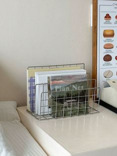 there is a metal basket on top of a bed next to a book rack with books in it