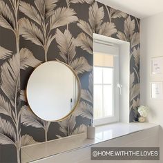 there is a mirror on the wall in this bathroom that has palm leaves painted on it