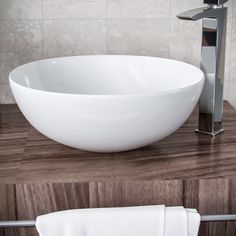 a white bowl sink sitting on top of a wooden counter next to a faucet