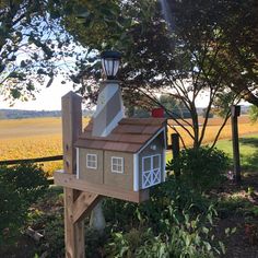 a birdhouse with a light on top in the middle of some bushes and trees