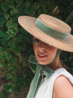 a woman wearing a straw hat with a green ribbon around the brim and neck