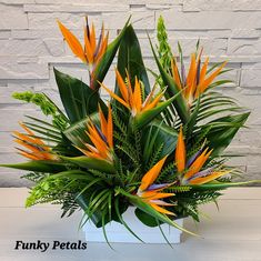 a white vase filled with orange and green flowers