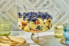 a dessert with blueberries and cream in a glass dish on a marble counter top