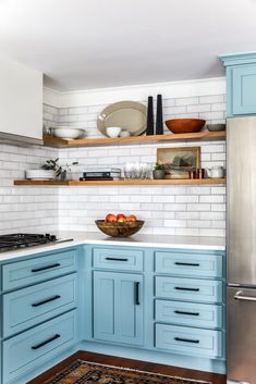 a kitchen with blue cabinets and stainless steel appliances in the center, along with an area rug on the floor