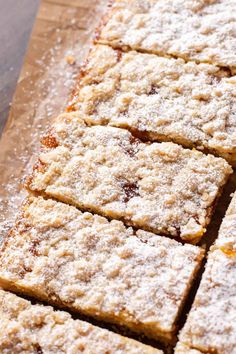 several pieces of cake sitting on top of a wooden cutting board with powdered sugar