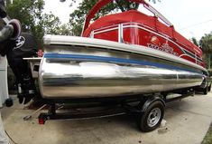 a silver and red boat is parked on the sidewalk next to a man in white