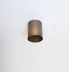 a light that is on the side of a white wall with a metal object hanging from it's ceiling