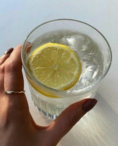 a person holding a glass with lemon in it