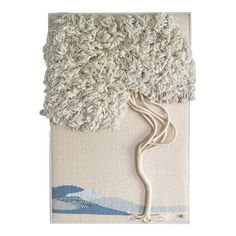 a white wall hanging with a tree on it's side and blue waves in the background