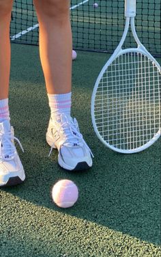 a person standing next to a tennis ball and racket on a court with grass