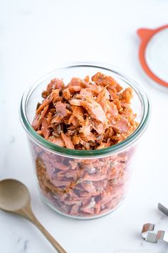 a glass jar filled with food sitting on top of a table next to a spoon