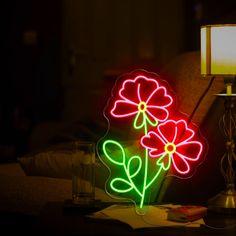 a neon flower sitting on top of a table next to a lamp